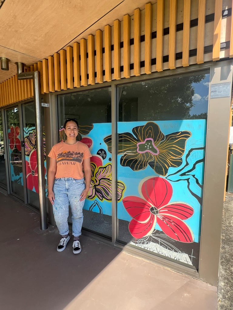 Lew standing in front of Pine Studio, Pine Rivers Park, Strathpine with a  colorful floral window mural. Commissioned by City of Moreton Bay Council. 